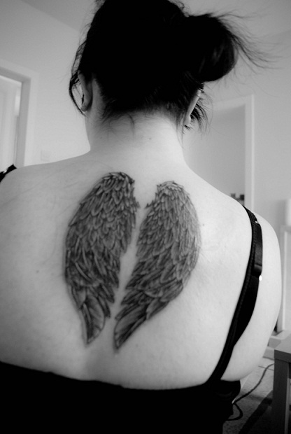 tattoo art depicting an angel's wings on the back of a woman's shoulder