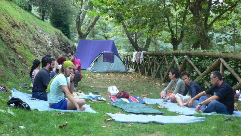 many people are camping and eating in the woods