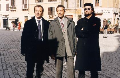 three men wearing business attire standing on a street