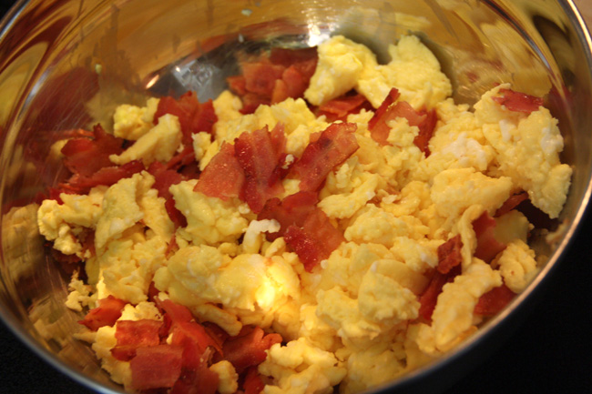 scrambled eggs and bacon cooking in an oven