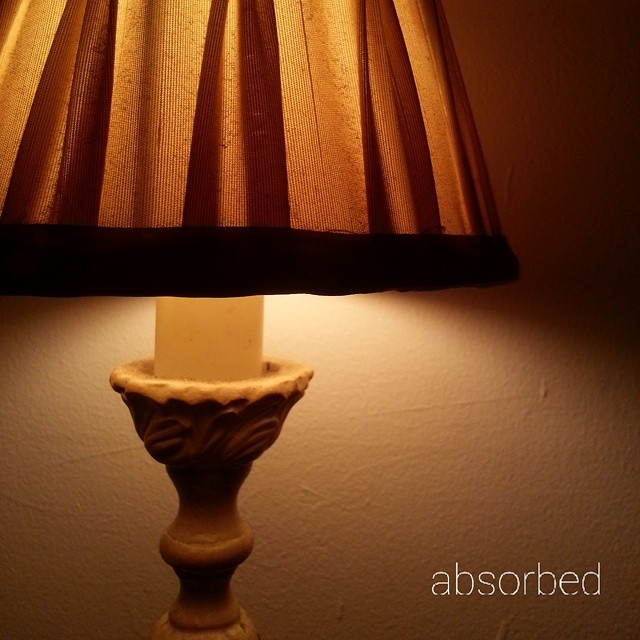 a beige ceramic vase sitting underneath a lamp