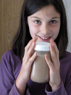 a little girl holding up a mason jar to her mouth