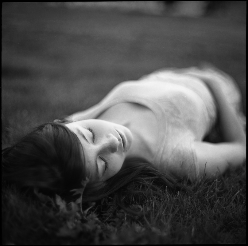 a woman is lying on grass with her eyes closed