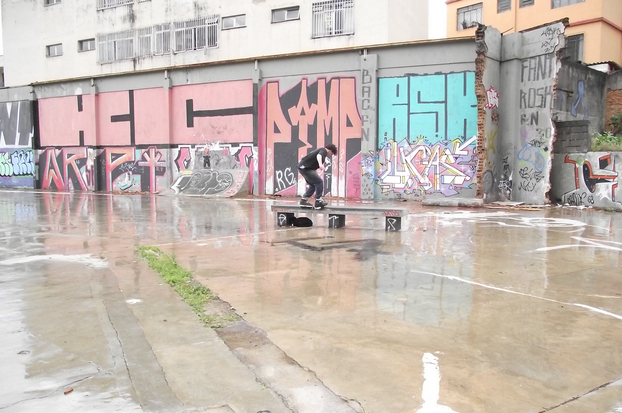 skateboarders skating on a wet concrete parking lot