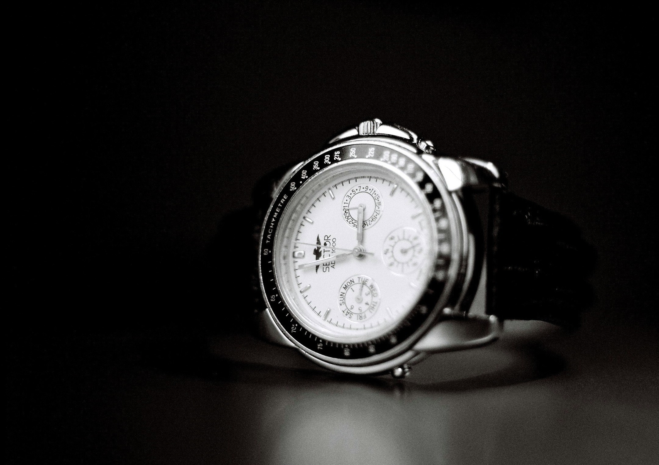 an analog watch sits in a dark spot