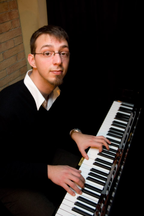 the young man is playing his organ in front of a black background