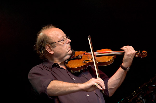 a man holding a violin while performing on stage