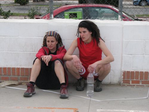 two young women sitting against the wall and waiting