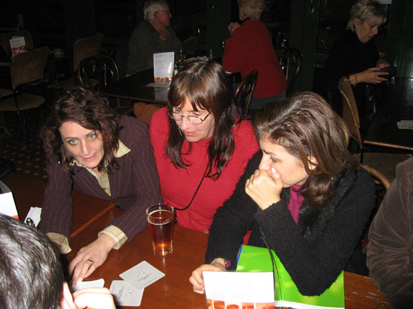 a group of women sitting around a wooden table with papers on it
