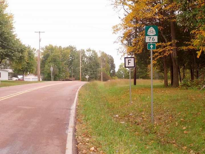 a street sign stands next to the rural road
