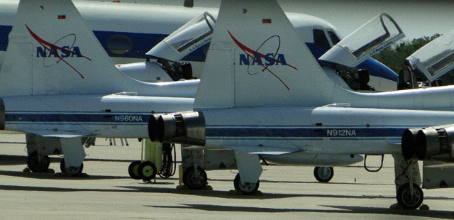small group of planes sit parked on a runway