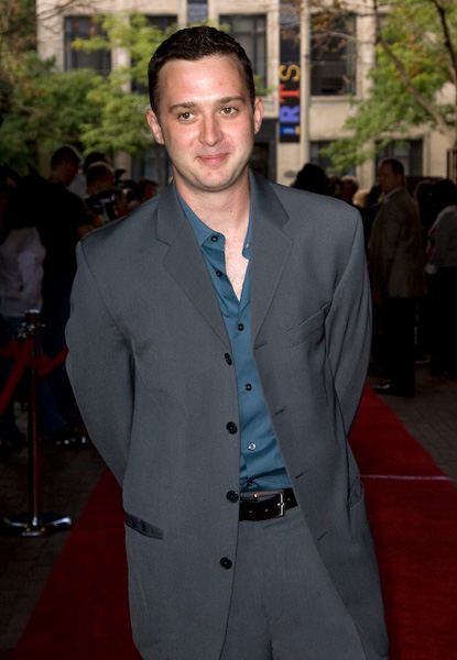 a man in a suit standing on a red carpet