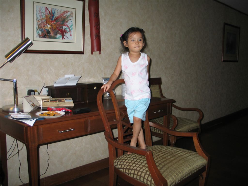 a little girl standing in front of a desk