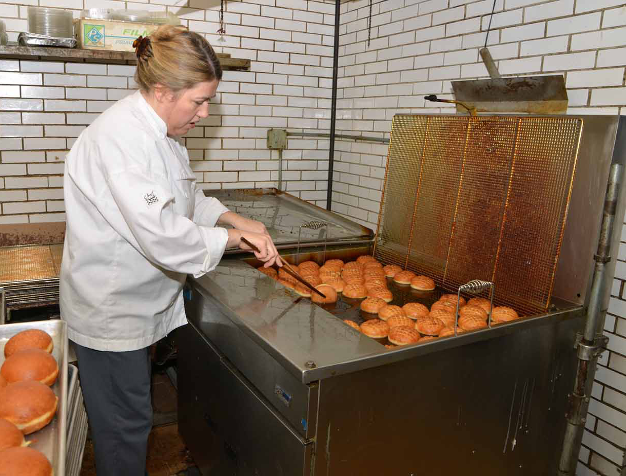 the woman is making donuts at the commercial pastry factory