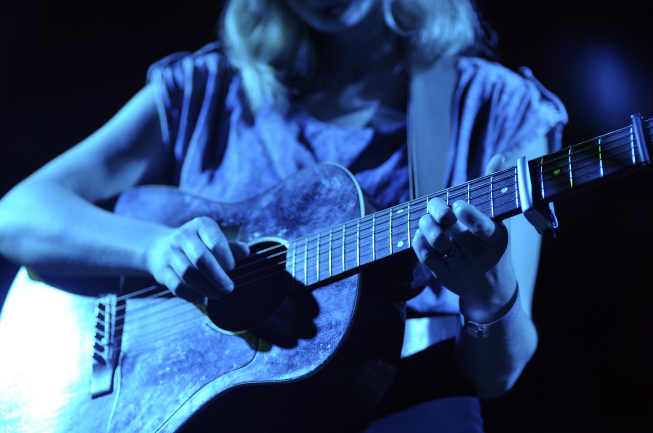 a woman playing the guitar on stage