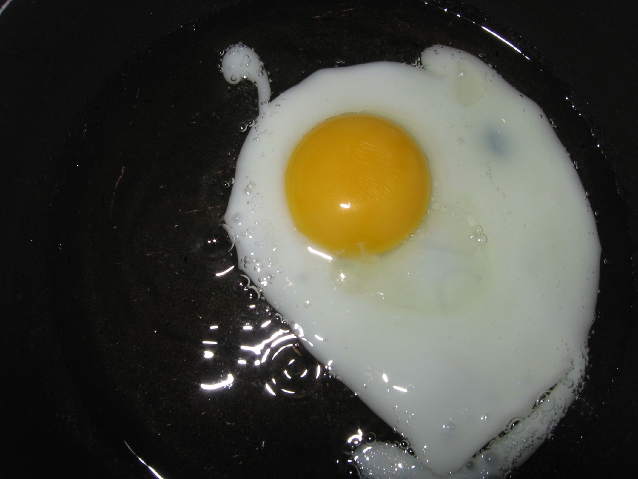 an egg frys in a set with melted oil on the side