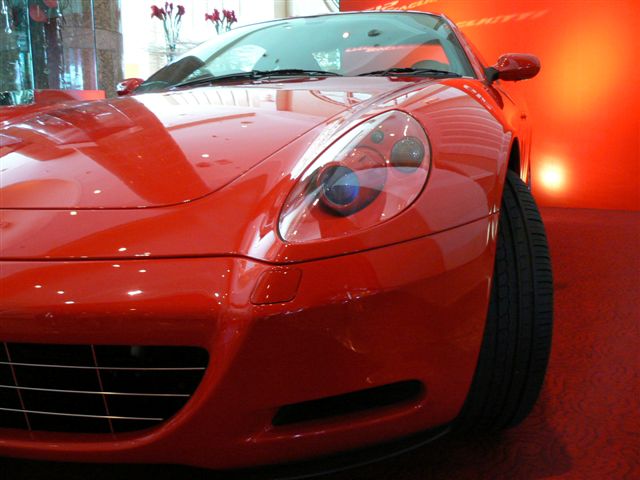 the front end of a red sports car in a showroom