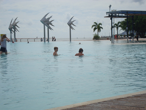 some people swimming in a big pool with sculptures around them