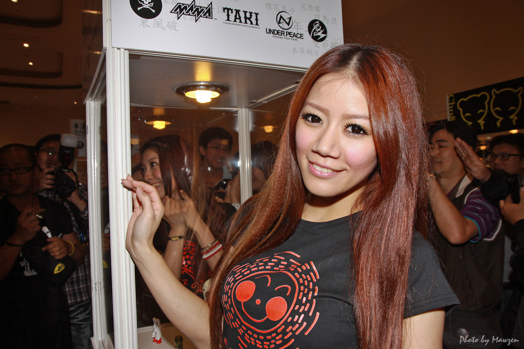 the woman has long hair and wears a red, orange, and black t - shirt