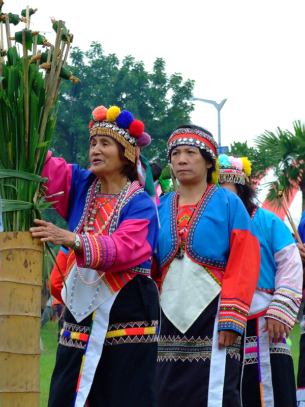 three people in colorful clothes carrying sticks and palm