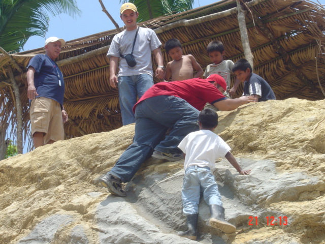 boys on rocks near thatch roof and palm trees