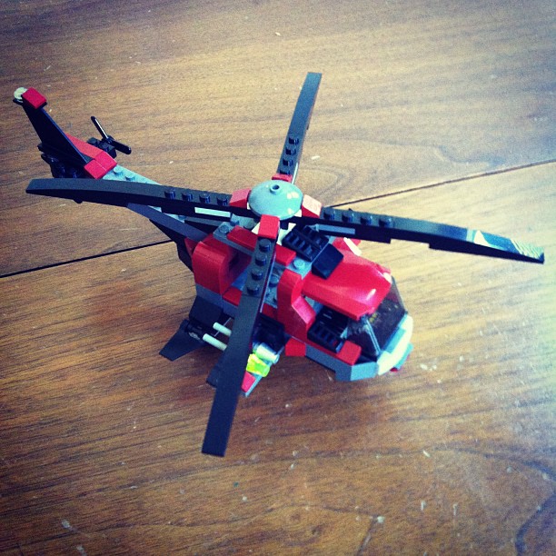 a lego helicopter on the ground with another object next to it
