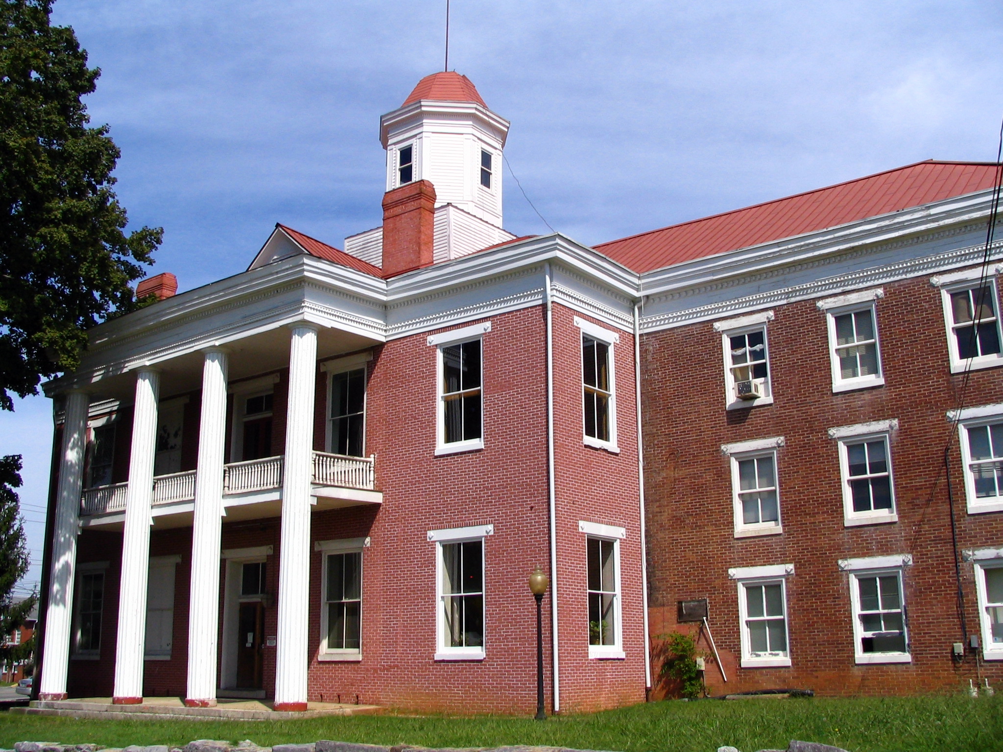 the front of a large red brick building with white columns