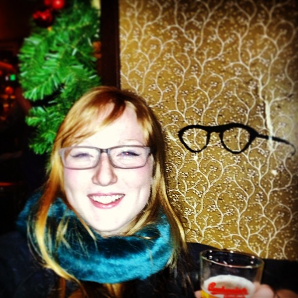 a woman in glasses holding a beer near a tree