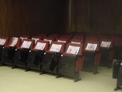 rows of empty red chairs with notepads on them