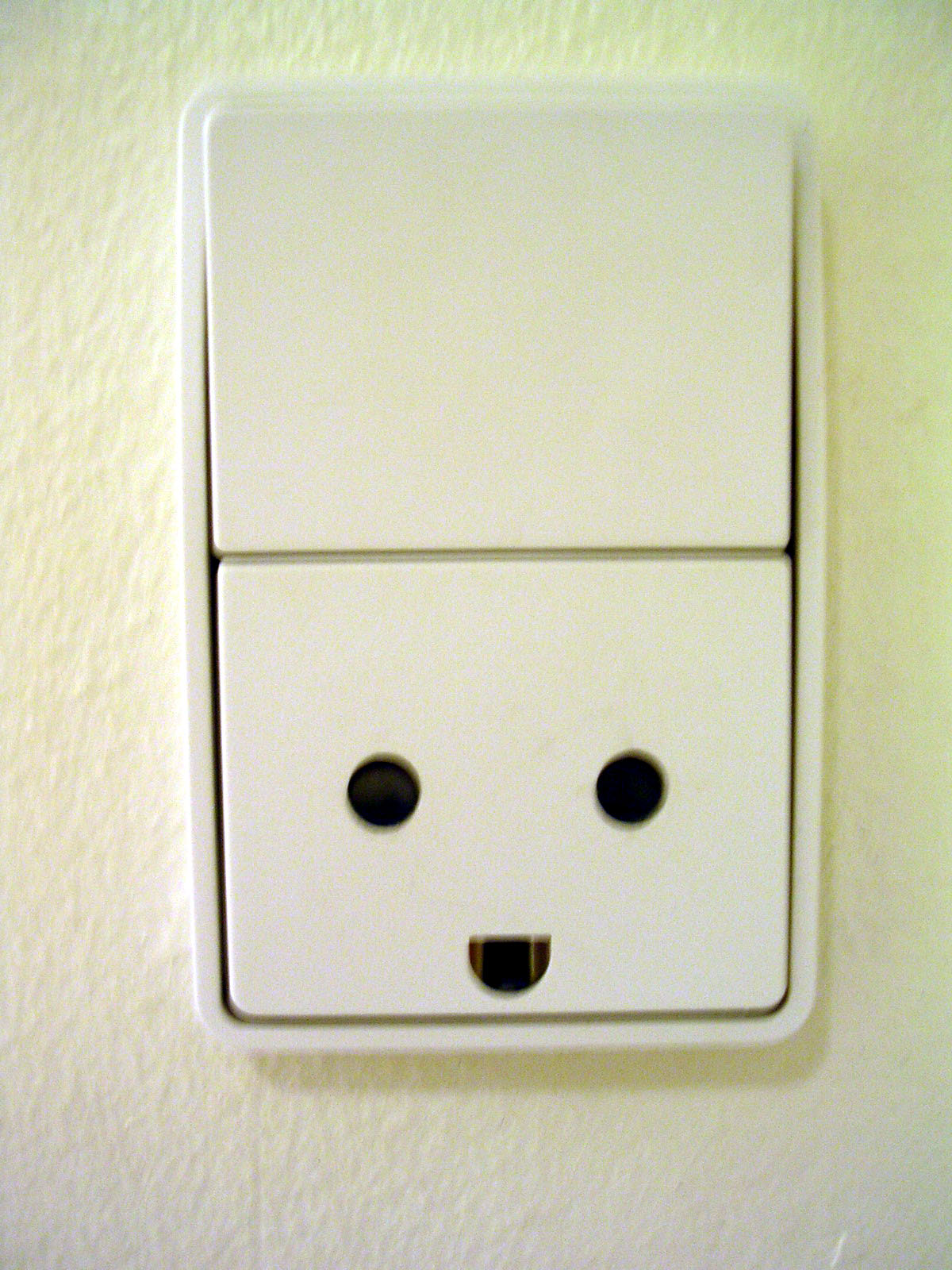a white light switch with two eyes on it