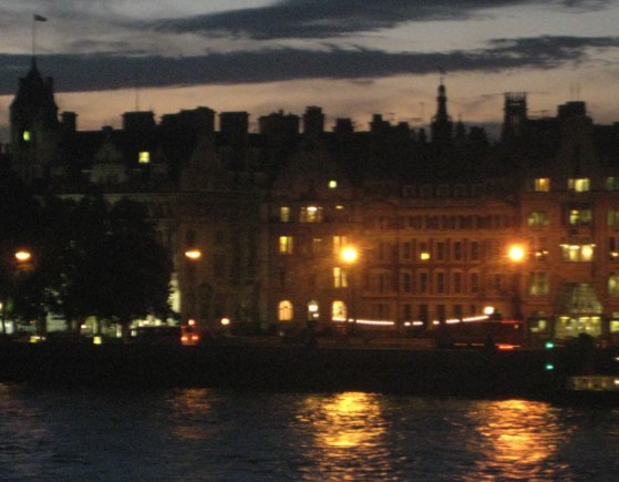 a row of lights shine on the buildings along the water