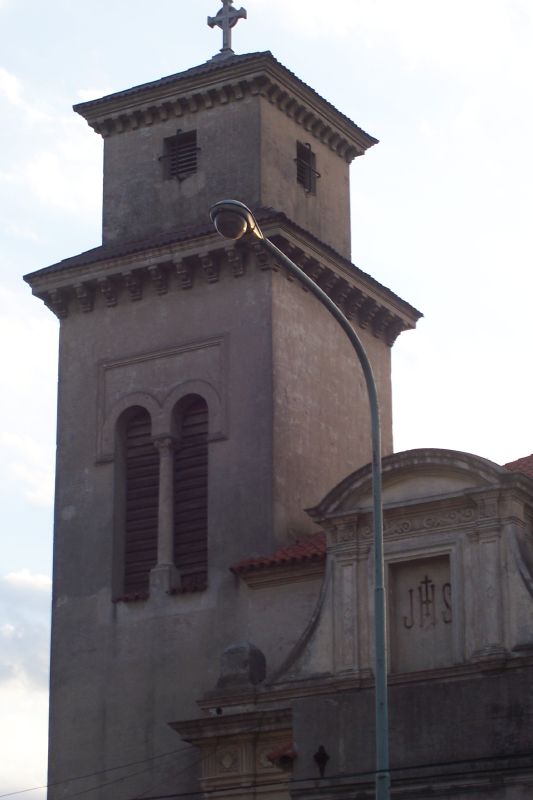 the large tower has a cross and is attached to it's side