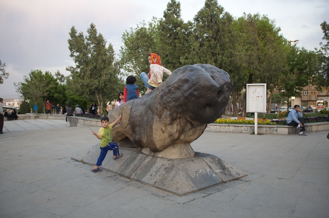 two children playing with the sculpture of a dog