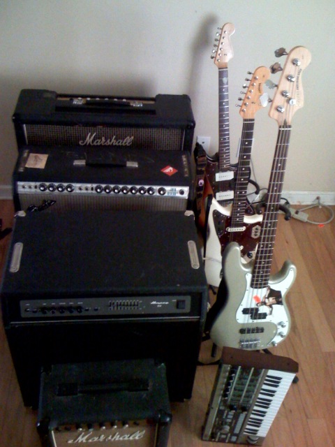 two electric guitars and amp on a wooden floor