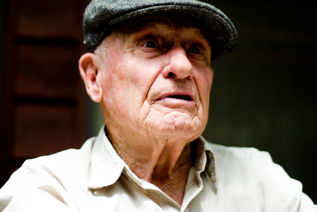 an older man in a brown shirt and cap