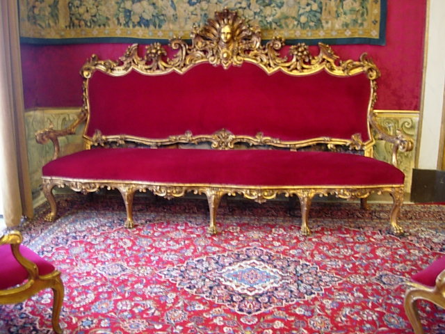 an old gold and red couch with fancy details