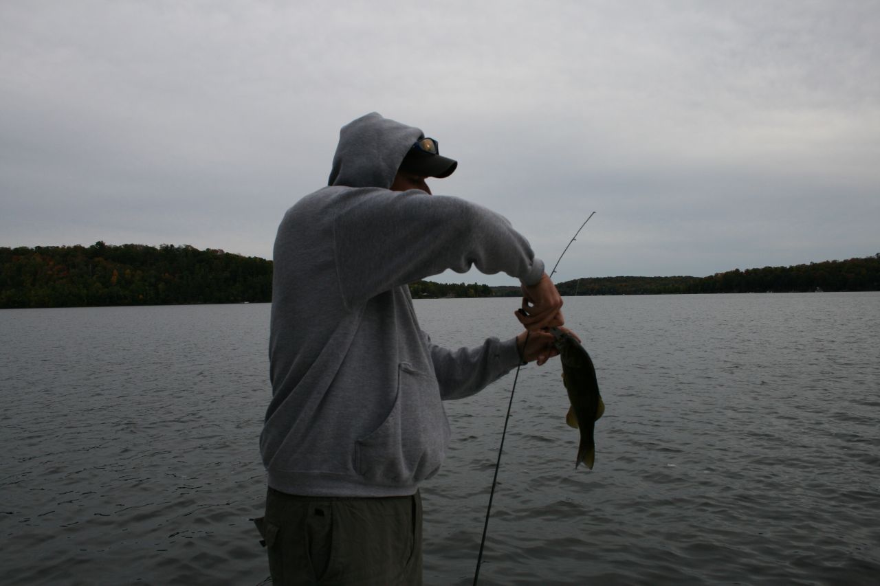 a man is holding up a fish on the water