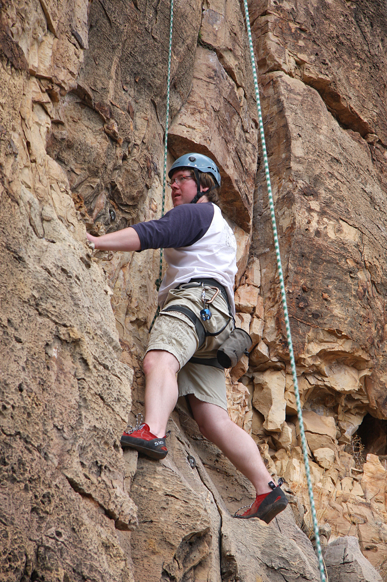 the man is climbing on the rope near some rock