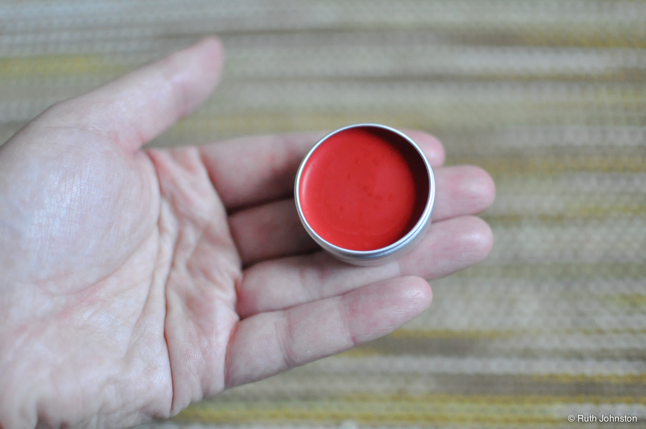 a man's hand holding a small red ring
