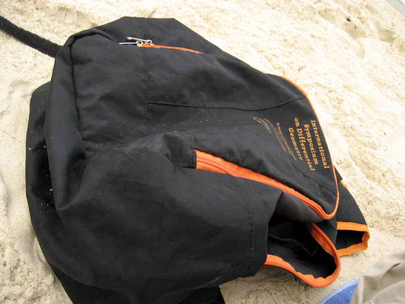 a book in a black backpack on a beach