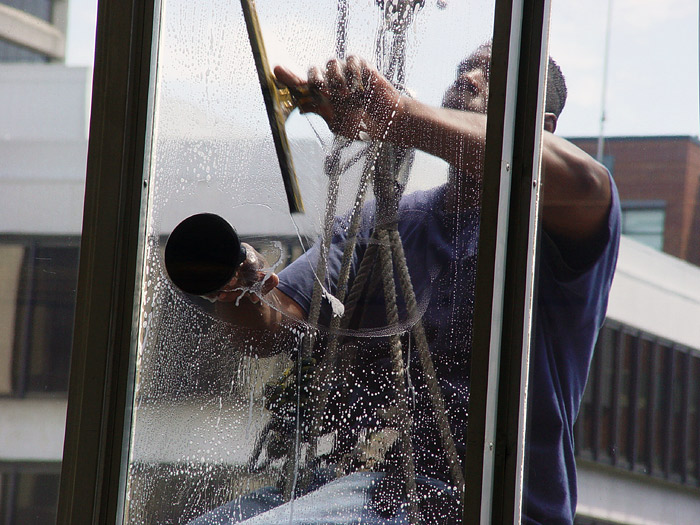 a man cleaning glass with a water hose
