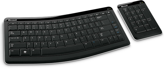 a wireless keyboard next to a black mouse and keyboard