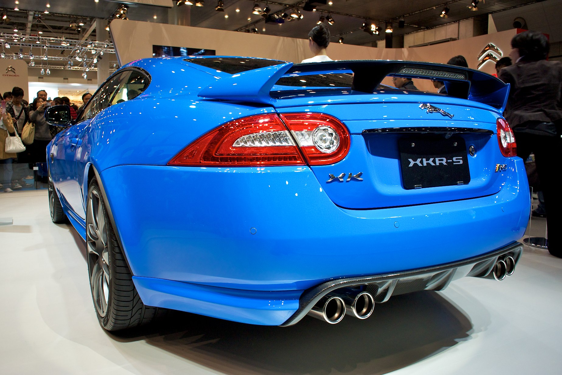 people are looking at the rear end of a blue sports car