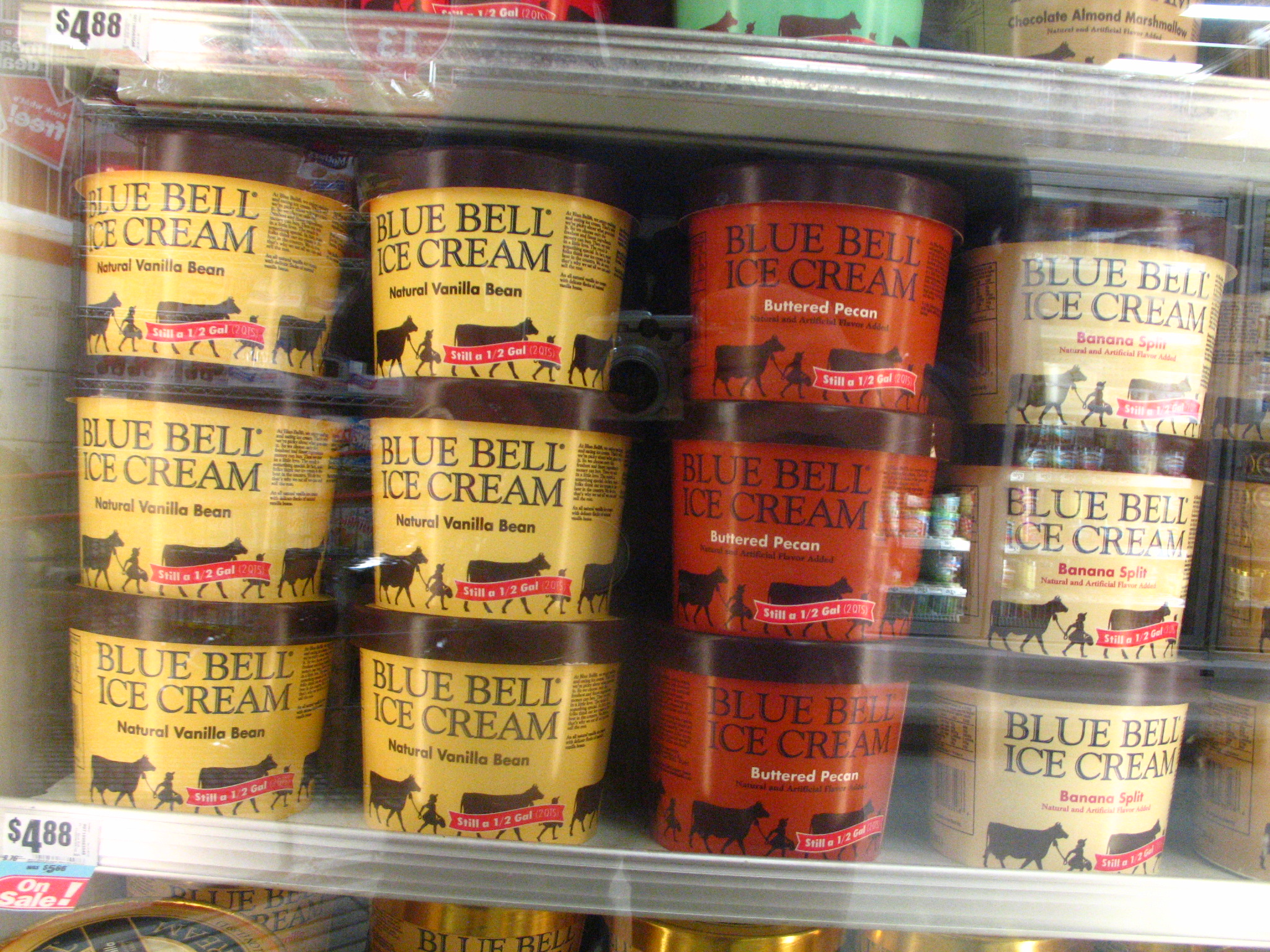 several different flavors of ice cream stacked in rows on the shelf