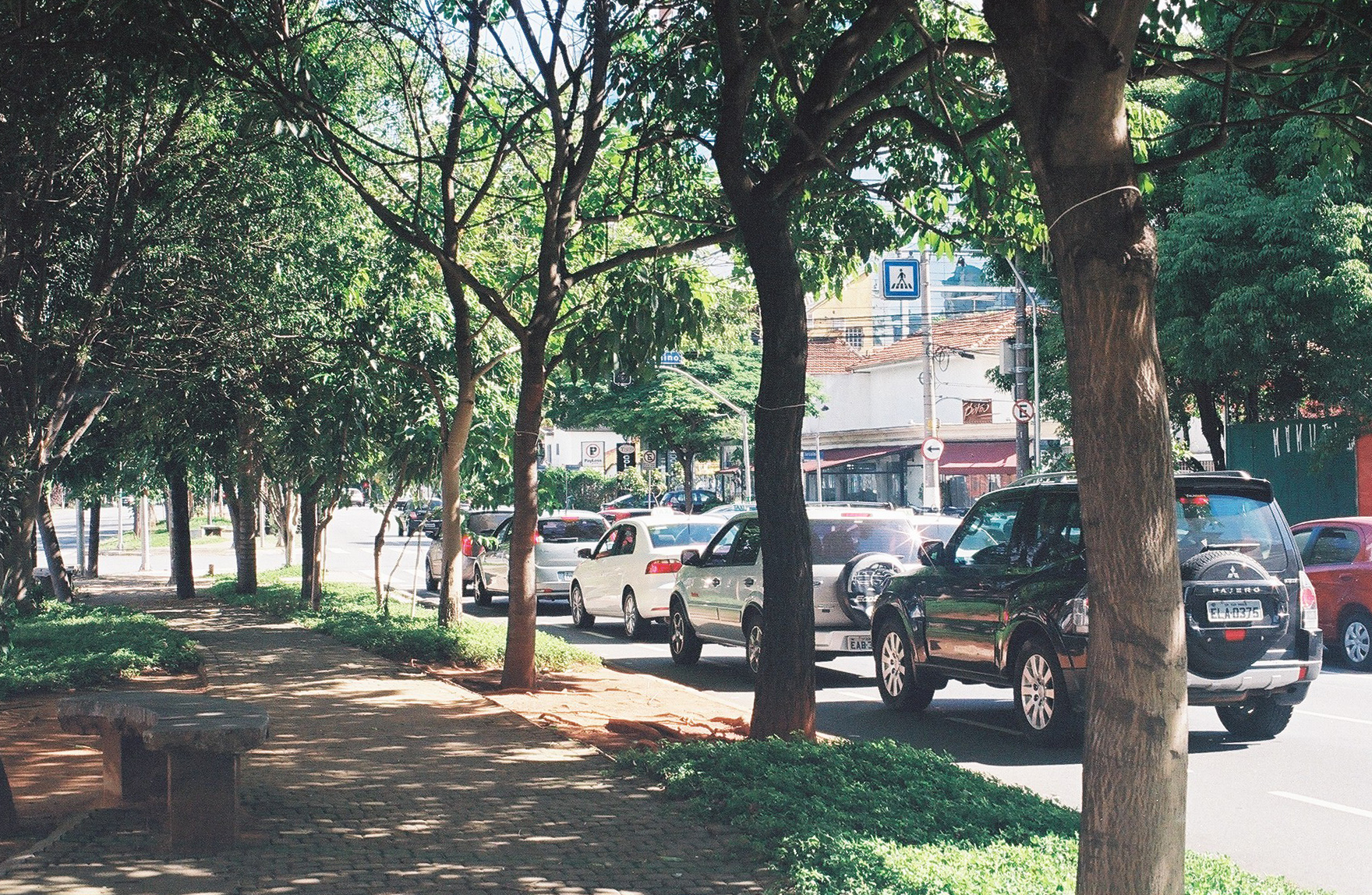 cars and trucks are lined up along a sidewalk in the middle of an urban area