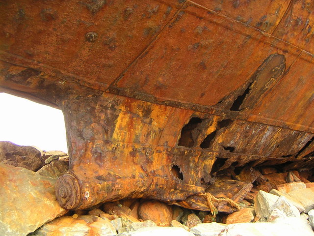 the bottom part of an old boat that is rusting and rotting