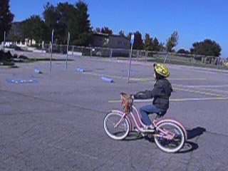 a little girl rides her bike around the parking lot