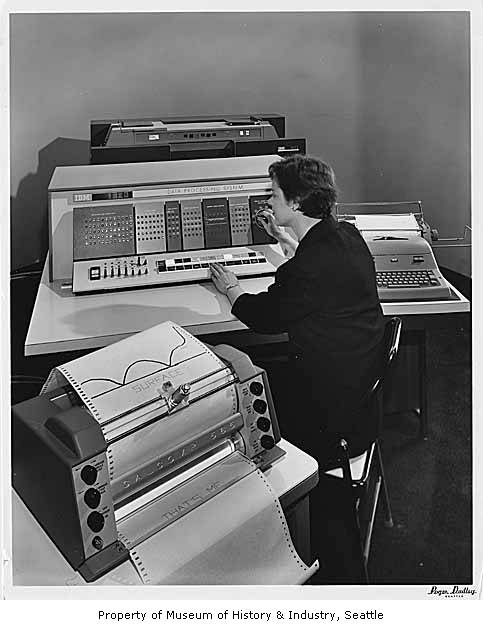 a woman sitting at a computer surrounded by papers