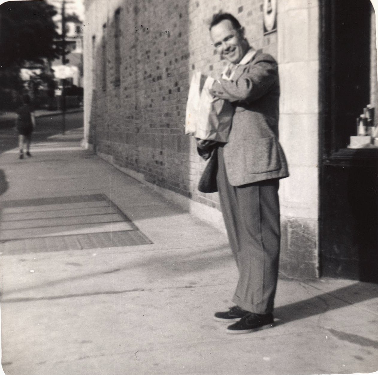 a man standing on the sidewalk and leaning on a wall