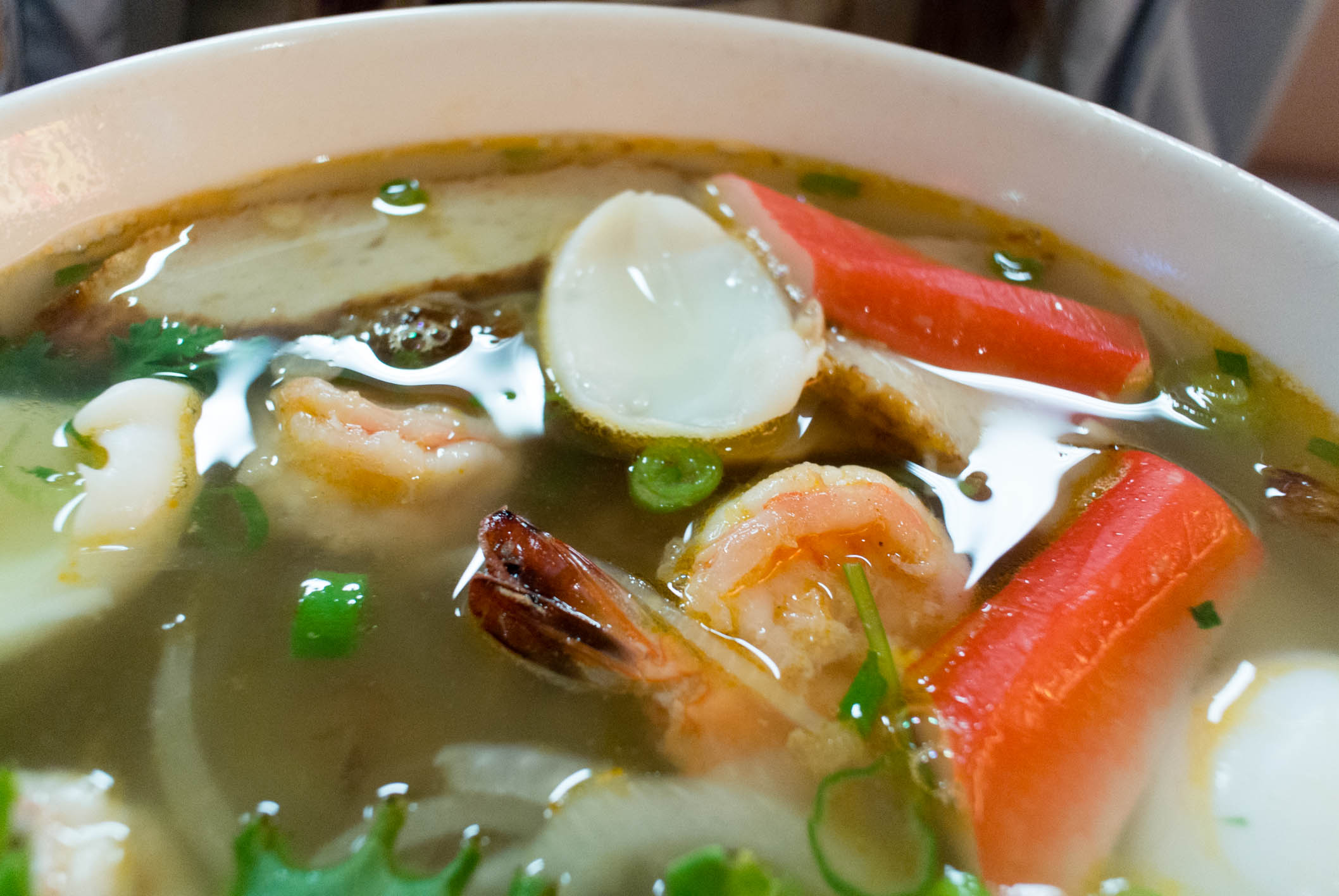 a bowl of soup with shrimp, carrots and noodles
